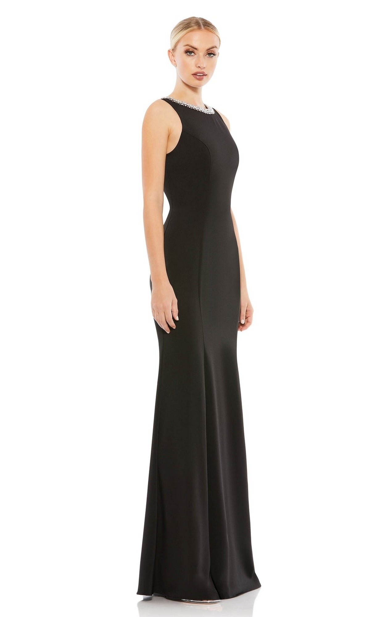A woman wearing the Mac Duggal 49093 Beaded-Neck Long Prom Dress, a sleeveless, floor-length black gown with a fitted silhouette, stands against a plain white background.
